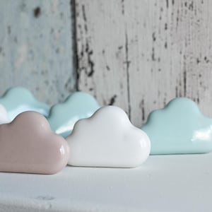May include: A collection of ceramic cloud-shaped ornaments in white, light blue and pink.