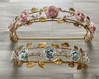 Może przedstawiać: Złota metalowa karnisz z kwiatowym motywem z różowymi i niebieskimi porcelanowymi różami. Karnisz jest zakrzywiony i ma ozdobny wzór.