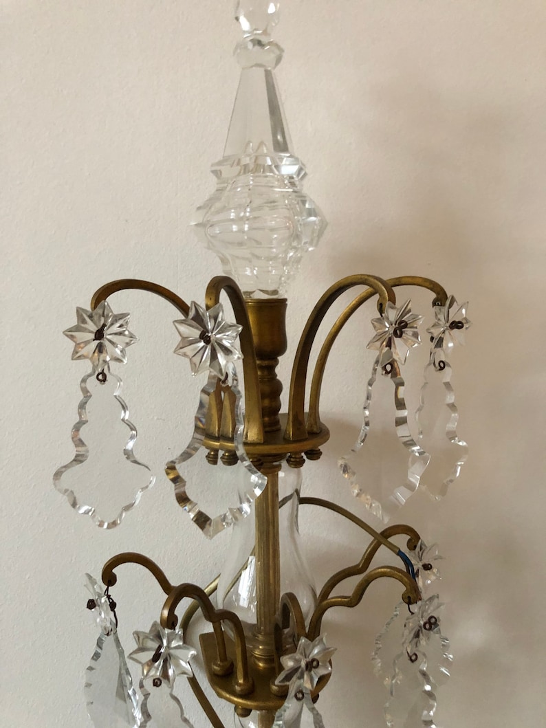 Peut inclure: Un lustre en m&eacute;tal dor&eacute; avec une pointe en cristal clair et plusieurs gouttes de cristal. Le lustre a un design traditionnel avec des d&eacute;tails orn&eacute;s.