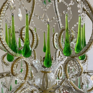 May include: A chandelier featuring a gold-toned metal frame adorned with numerous clear glass beads and vibrant green teardrop-shaped glass pendants. The structure includes curved metal arms, clear glass floral accents, and a central fluted glass base.