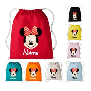 May include: A collection of drawstring bags in various colours including red, black, yellow, pink, teal, orange, white, and light blue. Each bag features a graphic of Minnie Mouse with a red and white polka dot bow and the word Name printed below.