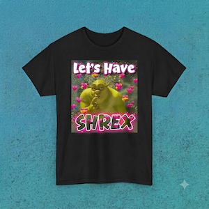 May include: A black short-sleeved t-shirt featuring a central graphic of the character Shrek with a finger to his lips. The text "Let's Have" appears above the character, and the word "SHREX" is printed below, surrounded by numerous pink hearts.