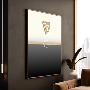 Guinness inspired “Split the G” poster framed in modern wooden frame and styled against dark wall interior, warm lighting casting shadows on minimalist black and cream pint inspired artwork, golden harp design at top, contemporary Irish décor, sophisticated Guinness wall art perfect for pubs, lounges, man caves, kitchens or living rooms, elegant beer lover gift, bold yet minimal statement piece celebrating Irish culture.