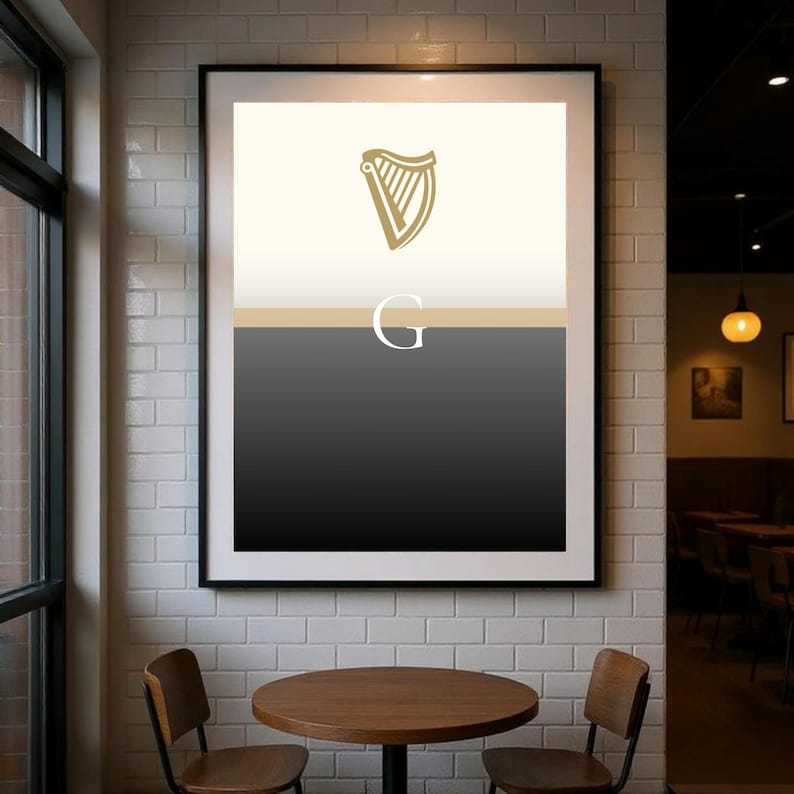 Modern framed Guinness inspired “Split the G” poster wall art hanging in a stylish café interior, minimalist black and cream design with golden harp icon, perfect Irish pub décor and beer lover gift print, ideal for Guinness fans who want contemporary artwork to celebrate Irish culture, displayed in cosy dining setting with industrial brick and wood textures for strong home or bar décor styling.