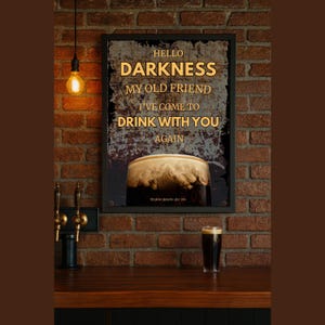 Guinness-inspired framed wall art poster styled against a warm-toned brick wall with vintage pendant lighting and a pint glass on a table below, creating a rustic home bar or speakeasy aesthetic.