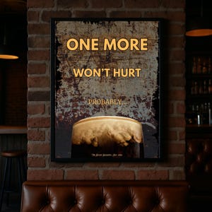 One More Won’t Hurt Probably framed poster displayed against an exposed brick pub wall with warm ambient lighting, showcasing bold typography and stout beer imagery, ideal for bar decor, man cave wall art, pub inspired home interiors and humorous gift ideas for beer drinkers
