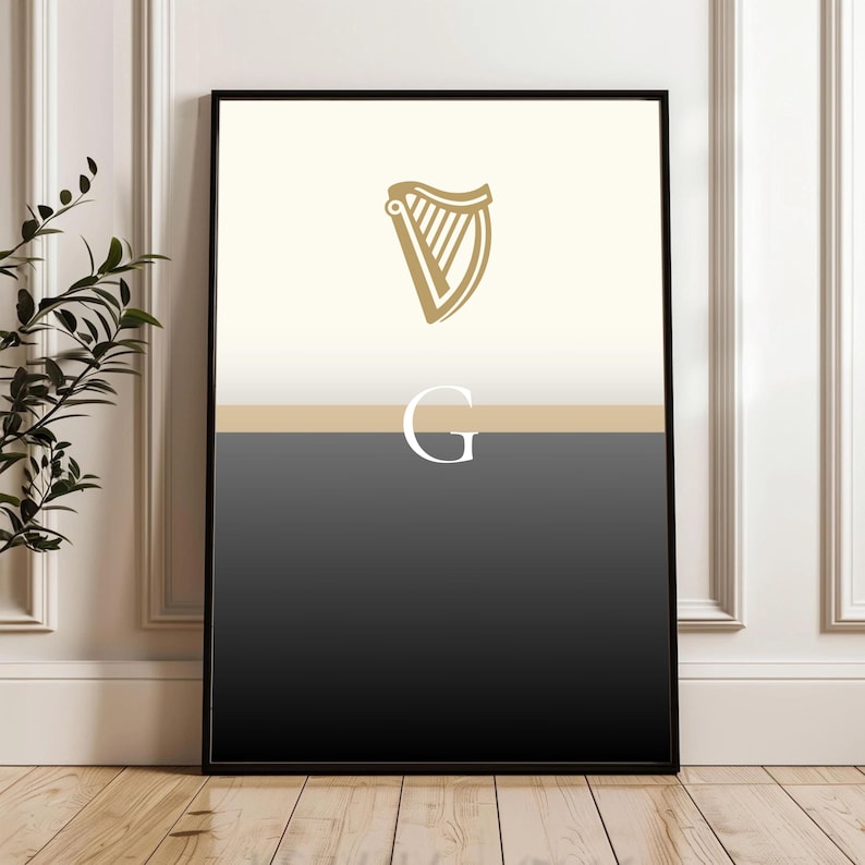Framed Guinness inspired “Split the G” poster displayed in elegant white wall room with modern wood flooring, black and cream pint inspired minimal design with golden harp, leaning casually against skirting board, contemporary Irish wall décor, perfect Guinness fan gift, modern home or pub artwork, sleek minimal aesthetic for beer lovers, Irish culture art print, versatile poster to complement home bars, lounges and dining areas.
