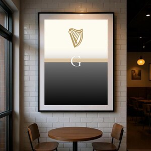 Modern framed Guinness inspired “Split the G” poster wall art hanging in a stylish café interior, minimalist black and cream design with golden harp icon, perfect Irish pub décor and beer lover gift print, ideal for Guinness fans who want contemporary artwork to celebrate Irish culture, displayed in cosy dining setting with industrial brick and wood textures for strong home or bar décor styling.