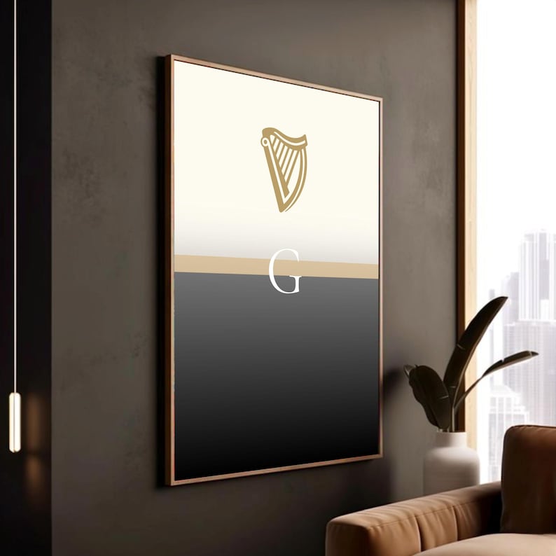 Guinness inspired “Split the G” poster framed in modern wooden frame and styled against dark wall interior, warm lighting casting shadows on minimalist black and cream pint inspired artwork, golden harp design at top, contemporary Irish décor, sophisticated Guinness wall art perfect for pubs, lounges, man caves, kitchens or living rooms, elegant beer lover gift, bold yet minimal statement piece celebrating Irish culture.