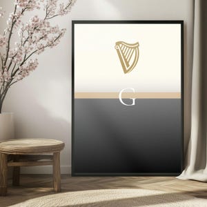 Guinness inspired “Split the G” wall art print in elegant bright interior with floral arrangement and wooden stool, framed minimalist pint inspired artwork with golden harp emblem, bold Irish culture décor, stylish Guinness themed artwork, modern gift for beer lovers, perfect for home bars, man caves, kitchens or dining spaces, sleek and minimalist Guinness inspired wall art print, contemporary Irish heritage poster for modern homes.