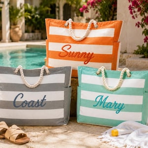 May include: Three rectangular canvas tote bags with horizontal stripes in orange, grey, and teal, each featuring white rope handles and side pockets. The bags are embroidered with the words Sunny, Coast, and Mary in a cursive script font.
