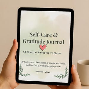 Può includere: Un tablet digitale che mostra un "Self-Care & Gratitude Journal" con testo in italiano. La copertina del diario presenta un simbolo a forma di cuore e il testo "30 Giorni per Riscoprire Te Stessa". Il tablet è tenuto in mano.