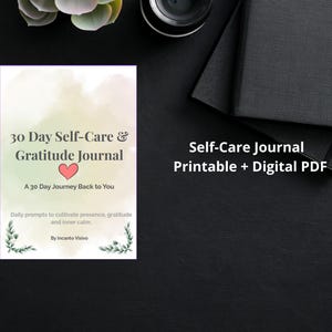 Può includere: Un diario bianco intitolato "30 Day Self-Care & Gratitude Journal" con un cuore. La copertina del diario riporta il testo "A 30 Day Journey Back to You" e "Daily prompts to cultivate presence, gratitude and inner calm." Sono visibili anche un taccuino nero e una fotocamera.