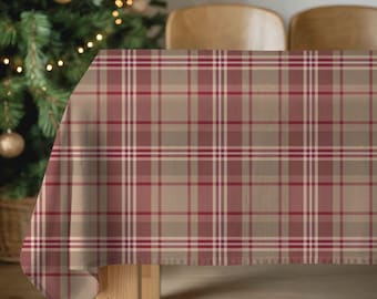 May include: A rectangular tablecloth with a plaid pattern in shades of red, white, and tan. The tablecloth is draped over a wooden table, with a Christmas tree visible in the background. The plaid design is a classic pattern.