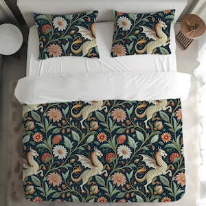 Op de afbeelding: Een donkerblauwe dekbedovertrek en twee kussenslopen met een herhalend patroon van draken, bloemen en bladeren. De draken zijn crèmekleurig met witte vleugels. De bloemen zijn in tinten roze, wit en oranje.