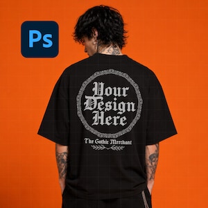 May include: A black t-shirt featuring a circular frame with the text Your Design Here in a gothic font. Below the circle, the text The Gothic Merchant is printed above a small leaf graphic. The shirt is shown from the back view on a person.