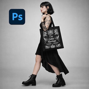 May include: A black tote bag with the text "The Gothic Merchant" and ornate illustrations is carried by a person wearing a black dress and boots. The bag is held over the shoulder. The Adobe Photoshop logo is in the upper left corner.