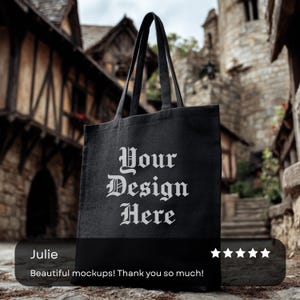 May include: Black tote bag with the text "Your Design Here" in white gothic font. The bag has long handles and is displayed against a blurred background of stone buildings. A customer review is visible at the bottom.