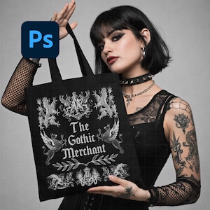 May include: Black tote bag with the text "The Gothic Merchant" and ornate white illustrations of mythical creatures and heraldic designs. The bag has black handles and is held up by a person.