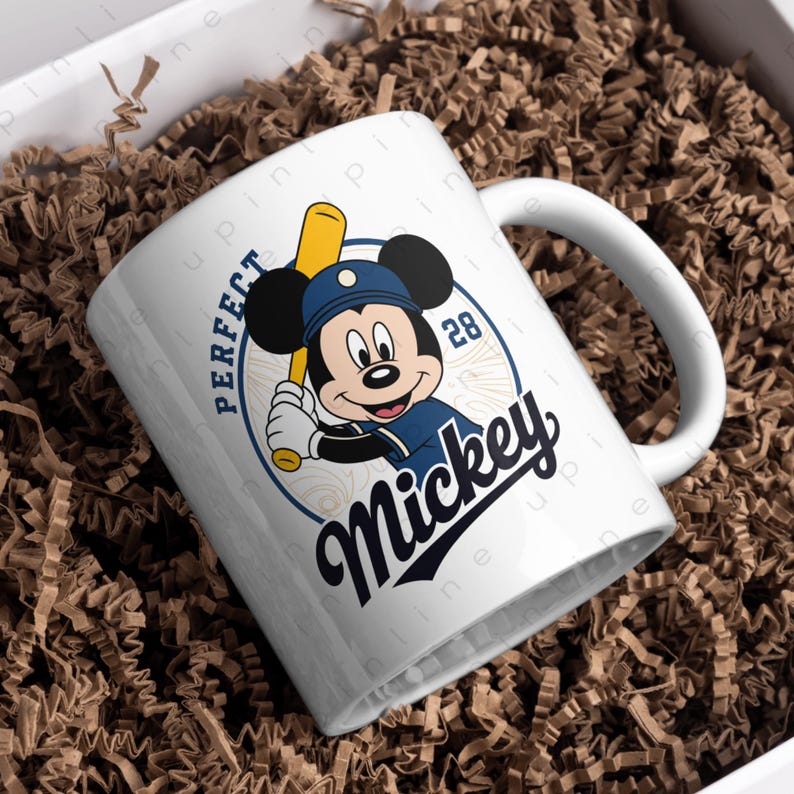May include: White ceramic mug featuring Mickey Mouse in a baseball uniform, holding a bat. The mug has the text "PERFECT Mickey" in navy blue and white. The number "28" is also included in the design.
