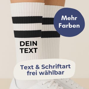 Könnte beinhalten: Weiße Socken mit schwarzen Streifen und dem Text "DEIN TEXT". Ein marineblauer Kreis mit den Worten "Mehr Farben" ist sichtbar. Der Text "Text & Schriftart frei wählbar" ist ebenfalls vorhanden.