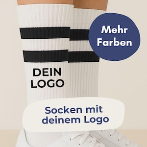 Könnte beinhalten: Weiße Sportsocken mit schwarzen Streifen und dem Text "DEIN LOGO". Die Socken werden mit weißen Turnschuhen kombiniert. Ein blauer Kreis mit dem Text "Mehr Farben" ist sichtbar. Der Text "Socken mit deinem Logo" ist ebenfalls sichtbar.