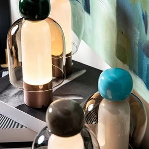 Peut inclure: Lampes de table décoratives au design unique. Chaque lampe est ornée d'un globe coloré sur le dessus, d'une source de lumière cylindrique et d'un abat-jour en verre transparent. Les lampes dégagent une lueur chaleureuse et invitante.