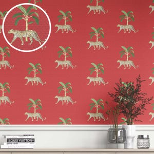 May include: Red wallpaper featuring a repeating pattern of leopards beneath palm trees. The leopards have a spotted coat and are in a walking pose. The palm trees have green leaves and brown trunks. The background is a solid red color.
