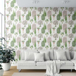 May include: White wallpaper with a repeating pattern of green and pink trees. The trees are stylized with various shapes and sizes. A white sofa with white pillows and a white blanket is in front of the wallpaper.