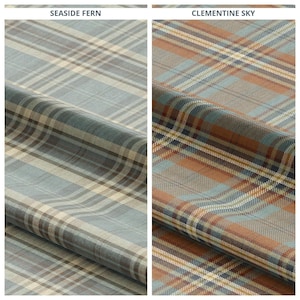 Puede incluir: Dos muestras de tela con patrones de cuadros. La muestra "Seaside Fern" presenta un estampado de cuadros azul, marrón y crema. La muestra "Clementine Sky" tiene un diseño de cuadros en tonos naranja, azul y marrón. Ambas telas están dobladas.