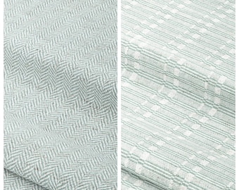 May include: Two fabric samples, one with a herringbone pattern and the other with a grid pattern. The herringbone fabric is labelled "PARADISE SKY" and the grid fabric is labelled "BEACHSIDE DRIVE". Both fabrics are light blue and white.