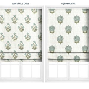 Pode incluir: Duas cortinas de janela com padrões florais. A cortina esquerda, rotulada como "Windmill Lane", apresenta um padrão repetitivo de flores azuis sobre um fundo creme. A cortina direita, rotulada como "Aquamarine", apresenta um padrão floral semelhante.