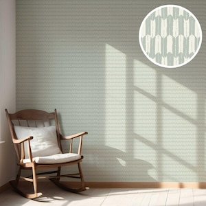 Op de afbeelding: Een kamer met lichtgroen behang met een subtiel geometrisch patroon. Een houten schommelstoel met een wit kussen staat voor de muur. Een cirkelvormige inzet toont een close-up van het behangontwerp.
