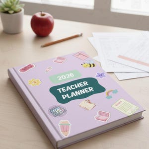 Puede incluir: Una agenda de profesor lila de 2026 con pegatinas coloridas, incluyendo una abeja, una flor y un arcoíris. Una manzana roja, un lápiz y una pequeña planta en maceta están sobre la superficie de madera. La portada dice "Teacher Planner".