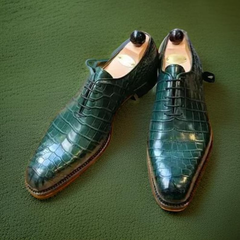 May include: A pair of green leather lace-up shoes with a crocodile pattern.