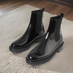 Puede incluir: Un par de botines Chelsea de cuero negro con paneles laterales elásticos y una suela de goma gruesa.