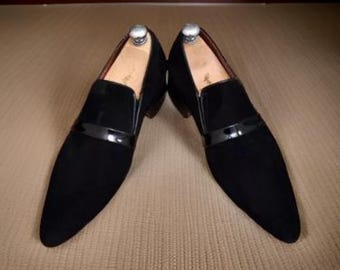 May include: A pair of black suede slip-on shoes with a pointed toe and a black patent leather trim.
