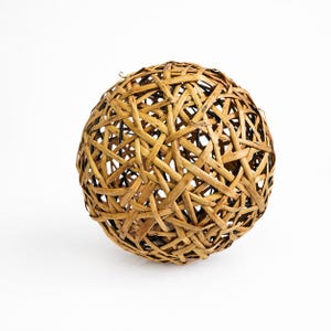 Puede incluir: Objeto decorativo esférico hecho de material tejido de color marrón claro y aspecto natural. El diseño entrelazado crea un patrón abierto en forma de celosía. La esfera está sobre un fondo blanco liso.