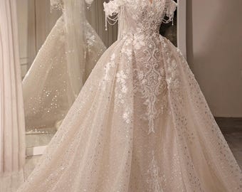 Vestido de novia de sirena con encaje color piel, escote corazón, hombros descubiertos, sobrefalda de tul desmontable con cola.