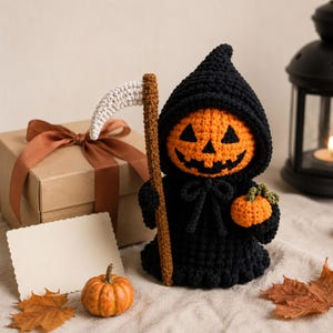 Peut inclure: Une figurine crochetée représentant une tête de citrouille orange vif avec un visage noir cousu, vêtue d'une cape à capuche noire. La figurine tient une faux au manche marron avec une lame blanche et une petite citrouille orange.
