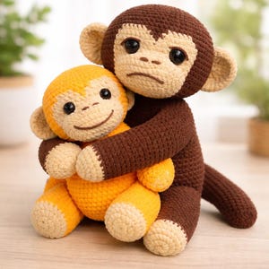 May include: Two crocheted monkey dolls. One is brown and beige, hugging a smaller orange and beige monkey. The monkeys have black eyes and are sitting on a wooden surface. The larger monkey has a slightly sad expression.
