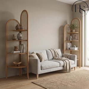 May include: A light grey sofa with a beige throw and cushions is positioned in front of two wooden shelves. The shelves display vases, books, and plants. A woven rug is on the floor.