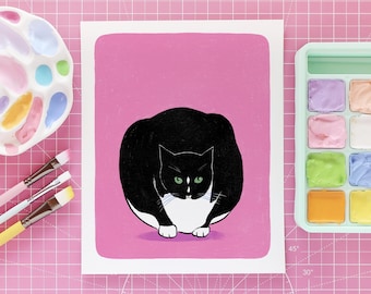 Könnte beinhalten: Eine Illustration einer schwarz-weißen Katze mit grünen Augen auf rosa Hintergrund. Das Kunstwerk befindet sich auf weißem Papier. Pinsel, eine Palette und eine Aquarellfarbenschale sind ebenfalls zu sehen.