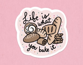 Może przedstawiać: Naklejka z różowym tłem przedstawiająca różne wypieki, w tym chleb, bułki i ciasteczka. Tekst "Life is what you bake it" jest napisany zabawną czcionką, otoczony kolorowymi posypkami.