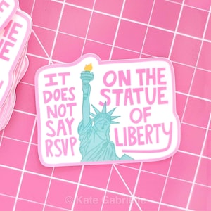 May include: A die-cut sticker with a pink border and the text "IT DOES NOT SAY RSVP ON THE STATUE OF LIBERTY" in pink and white. The Statue of Liberty is depicted in blue with a yellow torch. The sticker is on a pink grid.