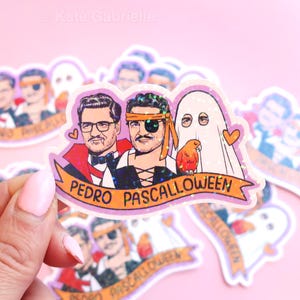 May include: A glittery sticker featuring three cartoon figures: a vampire, a pirate, and a ghost, with a small orange parrot. The sticker has the text "PEDRO PASCALLOWEEN" on a banner. The background is a light pink.