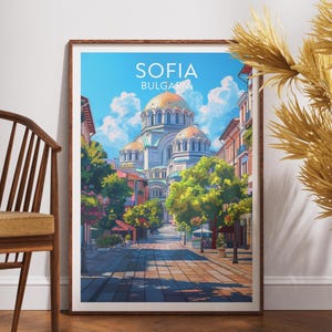 Puede incluir: Una impresión artística enmarcada que presenta una vibrante ilustración de Sofía, Bulgaria. La obra de arte muestra una gran catedral con cúpulas doradas, una calle arbolada y el texto "SOFIA BULGARIA" en la parte superior. La impresión se exhibe sobre un suelo de madera.