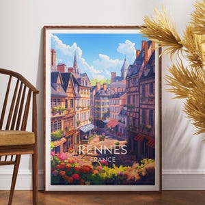 Puede incluir: Impresión artística enmarcada de Rennes, Francia, que representa una colorida escena callejera con edificios, tiendas y un cielo azul. La impresión incluye el texto "Rennes France" en la parte inferior y se muestra sobre un suelo de madera.