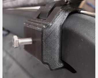 May include: Close-up of a black plastic car roof rack mount with a silver bolt. The mount is designed to attach to a car's roof rack.