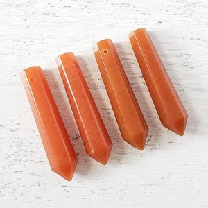 May include: Four orange carnelian crystal points with a hole drilled through the top for making jewelry or hanging as a charm.